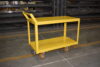 Steel two-tier shelf cart carrying automotive components through a doorway